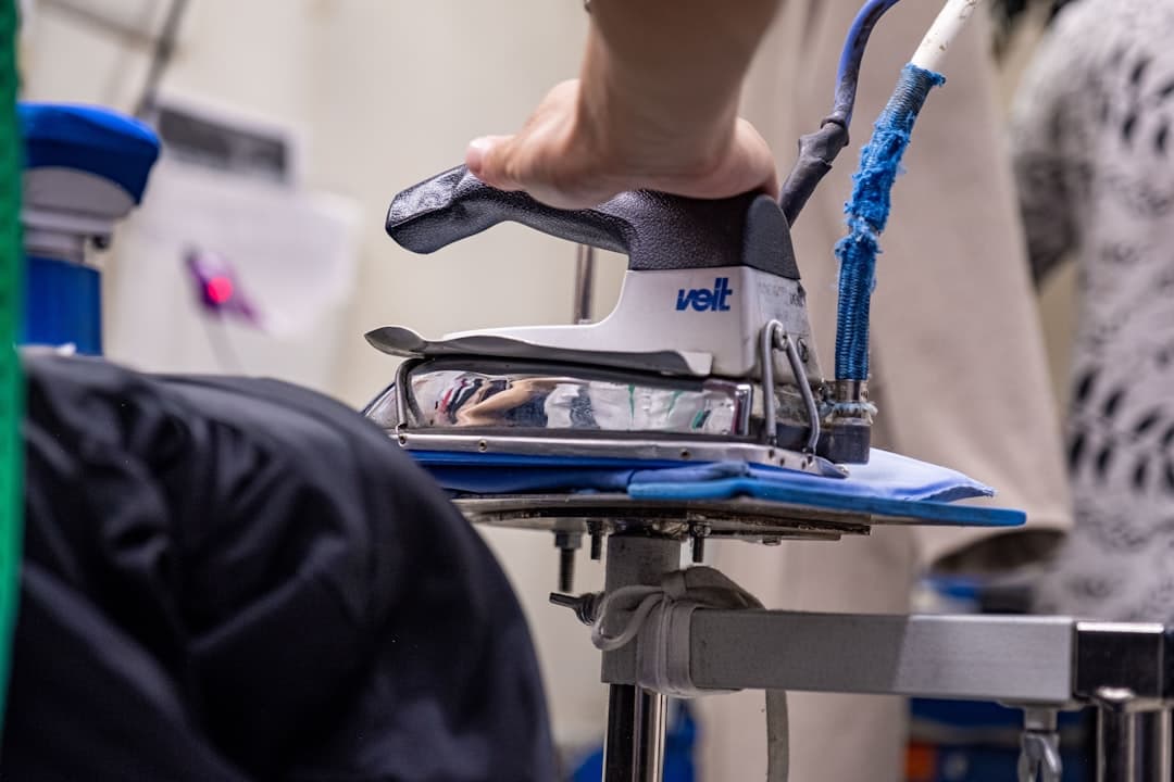 Industriellt ångstrykjärn pressar ett plagg på pressbordet